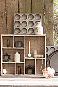Cake tins and ornaments on wooden shelf in UK garden
