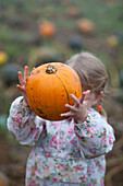 Girl holding pumpkin in October, UK