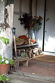 Brennholz und Fußmatte mit Gartengabel in der Veranda eines Bauernhauses, Vereinigtes Königreich