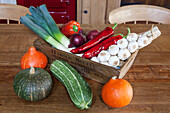 Frisches Gemüse in einer Kiste auf einem hölzernen Küchentisch in einer umgebauten Scheune in Surrey (England)