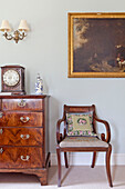 Polished wooden chair and set of drawers with gilt framed artwork in Wiltshire country house England UK