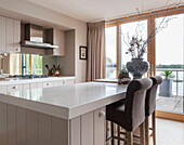 Frühstücksbar und Hocker mit Terrassentüren in der Küche eines Hauses in Lakeside, England, Vereinigtes Königreich