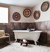 Freestanding bath with sheepskin rug and ethnic bowls in Lakes home, England, UK