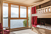 Bunkbed with red curtain at picture window in Lakes home, England, UK