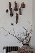 Wall-mounted collection of carved heads above branches in urn Hove home East Sussex England UK