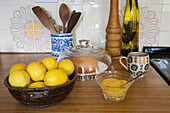 Zitronen in Schale mit Nieselkuchen und Tasse auf Küchenarbeitsplatte in historischem Landhaus in Somerset, UK