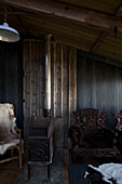Kaminofen und geschnitzter Sessel in umgebauter Scheune Dartmoor Devon England UK