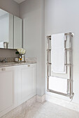 White bath towels on rail with mirrored cabinet in London home UK