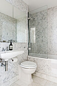 Light grey tiling and shower screen with mirrored cabinet in London bathroom UK