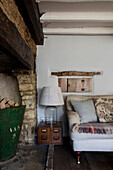 Lamp on antique filing box with metal log bucket and sofa in Cirencester farmhouse Gloucestershire UK