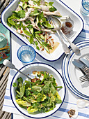 Blattgrüne Salate mit Metalltellern und Besteck auf einem Tisch