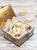 Dried apple in vintage metal storage tin with champagne in glasses Battersea London UK