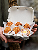 Woman holding egg box of battered scotch eggs Brighton, East Sussex UK