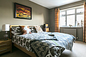 Patterned duvet and blanket on wooden bed with retro radios and lamp in Farnham home Surrey UK