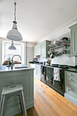 White pendant light above light green fitted island unit with black AGA in Winchester kitchen UK