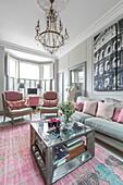 PInk hues and artwork with silver glass topped coffee table in living room of Victorian terrace Wandsworth London Uk
