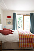 Rote Kissen mit kariertem Überwurf auf dem Bett im Ferienhaus auf der Isle of Wight