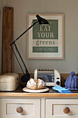 Fresh bread in kitchen with desk lamp and poster reading 'Eat Your Greens'