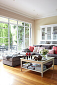 Glass topped coffee table with grey sofa and pink cushions in living room of Sydney home Australia