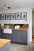 Grey fitted units with black and white family prints in Coombe cottage kitchen, UK