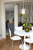 Dining table and chairs in room with patterned wall paper and metallic ceiling light, Coombe cottage, UK