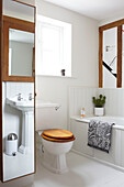 Mirrored full length storage cabinet in contemporary bathroom of Coombe country cottage, England, UK