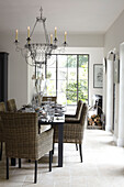 Dining table with wicker chairs and uncurtained picture window in Isle of Wight home, UK