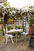 Blühender Jasmin mit schmiedeeisernem Tisch und Stühlen auf einer Veranda mit Spalier in einem Doppelhaus UK