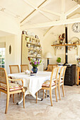 Wicker dining chairs at table in open plan Wiltshire country home, England, UK