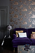 Vintage lamp with purple sofa with patterned wallpaper in retro-styled London living room, England, UK