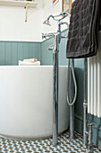 Black towel with chrome fittings at freestanding bath in London home, England, UK