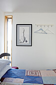 Patchworkdecke und Kunstwerk mit Kleiderbügeln im Schlafzimmer eines Hausboots in Bembridge, Isle of Wight, Großbritannien