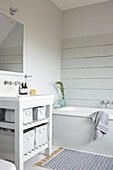 Mit Holz verkleidete Wände und Waschtisch mit Spiegel in einem Neubau auf der Isle of Wight, Großbritannien