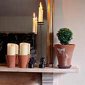 Terrakotta-Töpfe und Kerzen auf einem Marmormantel mit vergoldetem Spiegel