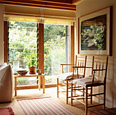 Modern country living room detail with shaker style carver chairs and slatted window overlooking the garden
