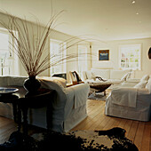 White spacious living room with wooden floorboards and animal skin rugs