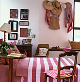 Country style pink and white bedroom with straw hats hanging on the wall