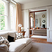 View into en suite bathroom from large bedroom with sofa by the window