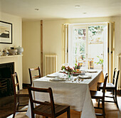 Klassisches weißes Esszimmer mit gedecktem Tisch zum Mittagessen und Tür zum Garten