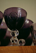 Detail of purple coloured glasses on a wooden shelf