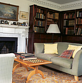 Grey sofas in front of fireplace in family sitting room with mahogany bookcase