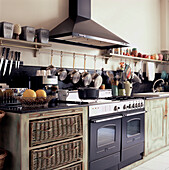 Double cooker set within custom built wooden kitchen units with wicker basket drawers