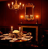 Elegant candlelit dinner in reddish brown wood panelled dining room