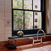 Kitchen sink in tiled kitchen with view of lightwell and bamboo plants 