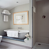 Roll top bath in modern white bathroom with walk in shower