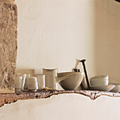Glazed ceramics on display along a wooden beam set in plastered wall 