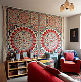 Ethnic wall hanging behind an eclectic mix of furniture in budget style living room
