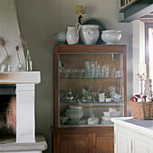 Detail of Tuscan kitchen with glass cabinet filled with crockery silverware and glass