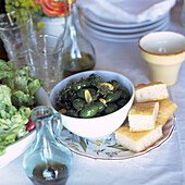 Ein Teller mit grünen Oliven mit Koriandersamen und Focaccia-Brot auf einem für das Mittagessen gedeckten Tisch