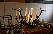 Table setting with 1950s Danish crystal lighted candles in African turned wood candlesticks and stag horn candelabras by